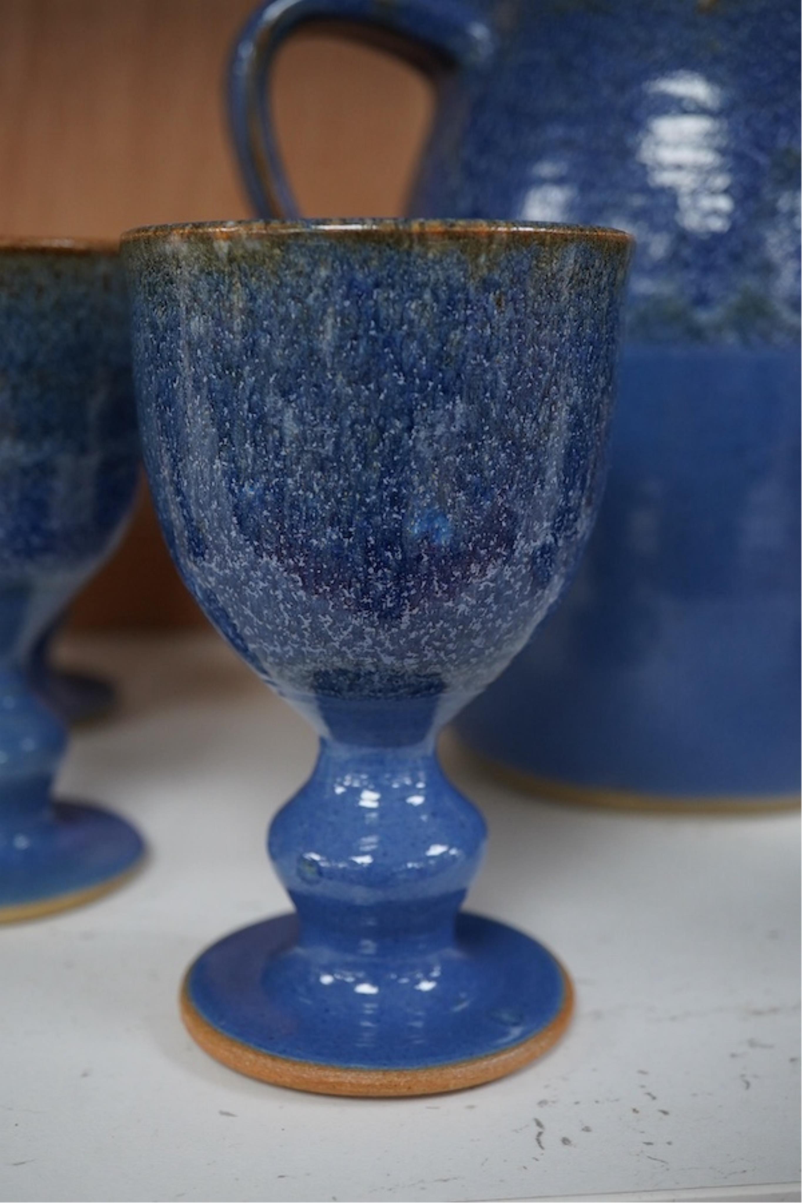 A Canterbury pottery, blue glaze jug and twelve goblets, jug 28cm high. Condition - fine chip to one goblet